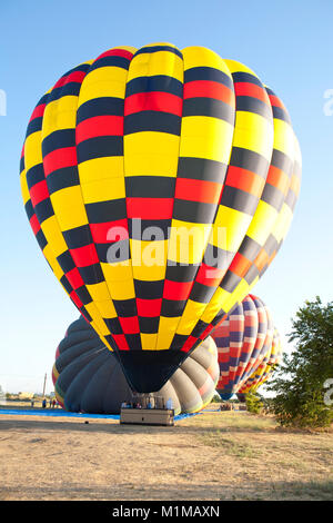 Montgolfières en vol avec des couleurs vibrantes contre tôt le matin, ciel bleu Banque D'Images