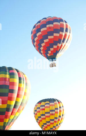 Montgolfières en vol avec des couleurs vibrantes contre tôt le matin, ciel bleu Banque D'Images