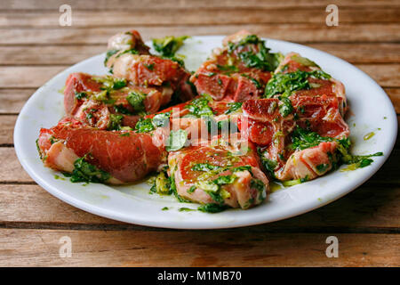 Lambchops mariné dans l'huile d'olive, basilic, citron et poivre sur une plaque blanche Banque D'Images