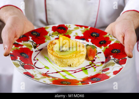 Cassolette de fromage, fraises, kiwis, fruits confits sur la plaque dans les mains du cuisinier Banque D'Images