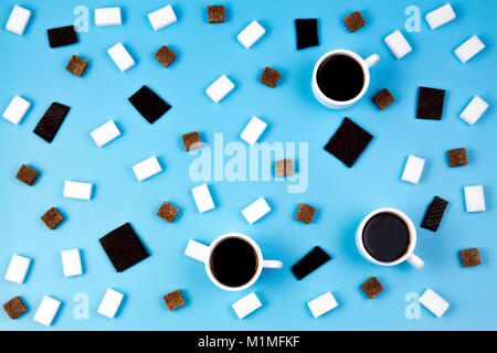 Du café et des sucreries. Tasses de café, les cubes de sucre brun et blanc et chocolat prieces sur fond bleu Banque D'Images