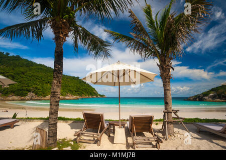 Une scène typique Belle maison de vacances avec deux chaises de plage et un parasol au milieu, entourée de palmiers, offrant une très belle vue sur la plage. Banque D'Images