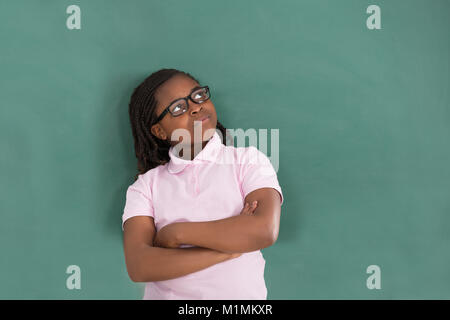 Close-up of African Girl standing contre le Green Chalkboard In Classroom Banque D'Images
