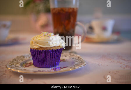 Délicieux cupcake à la crème de vanille sur une table en dentelle ancienne vintage chiffon et plateau de fruits à l'arrière-plan avec des fleurs fraîches Banque D'Images