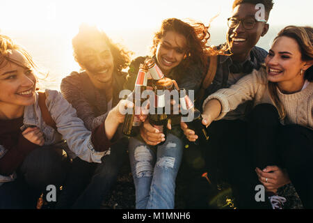 Groupe multiethnique de people toasting outdoors bières. Smiling young les hommes et les femmes à faire la fête un jour d'été. Banque D'Images