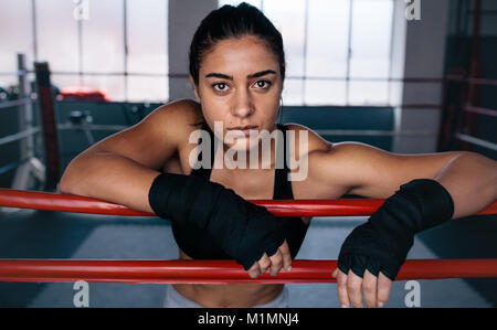 Close up of a female boxer debout à l'intérieur d'un ring de boxe. Repos Boxer ses bras sur la corde du ring de boxe. Banque D'Images