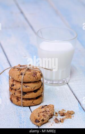 Pile de cookies aux pépites de chocolat avec un verre de lait frais sur la table en bois bleu Banque D'Images