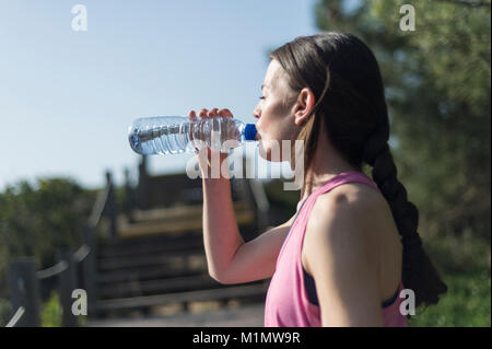 Femme buvant de l'eau d'une bouteille après l'exercice. À l'extérieur. Banque D'Images