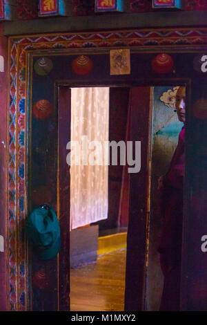 Bumthang, Bhoutan. Jeune homme à l'entrée de Jambay Lhakhang temple. Banque D'Images