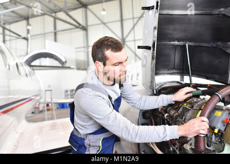 Mécanicien d'aéronefs répare un moteur d'avion dans un hangar de l'aéroport Banque D'Images