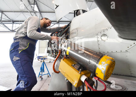 Mécanicien d'aéronefs répare un moteur d'avion dans un hangar de l'aéroport Banque D'Images