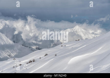 Granges et bâtiments de ferme parsemées à travers les champs couverts de neige près de la station de ski des Menuires dans les 3 vallées dans les Alpes Françaises Banque D'Images