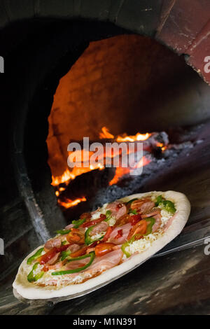 Pizza dans le poêle à bois avant la cuisson au feu de bois et contexte Banque D'Images