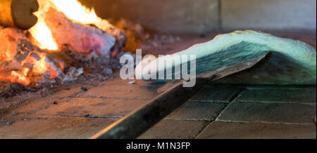 Pâte à pizza croustillante bas dans le poêle à bois pendant la cuisson avec le feu arrière-plan Banque D'Images