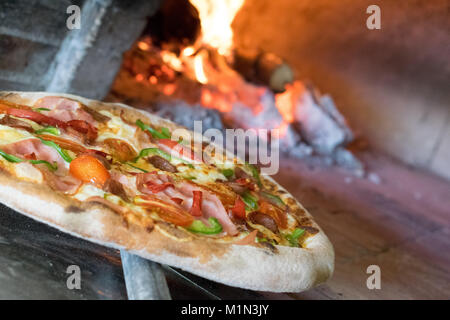 Délicieuse pizza après la cuisson dans la poêle avec le feu de bois et wood background Banque D'Images