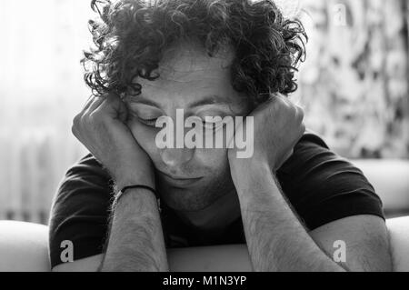 Seul et ennuyé young Caucasian man avec les cheveux bouclés à la chambre Banque D'Images