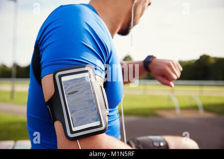 Le port de brassard smartphone athlète masculin contrôle smartwatch Banque D'Images