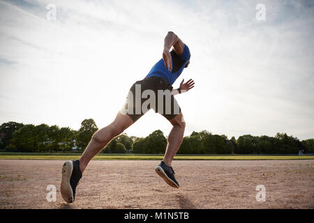 Jeune homme sportif tournant à une piste, low angle view Banque D'Images