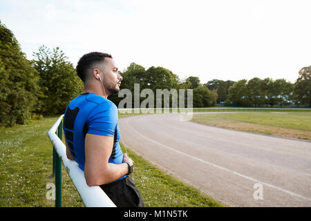 L'athlète masculin wearing earphones prenant une pause à une piste Banque D'Images