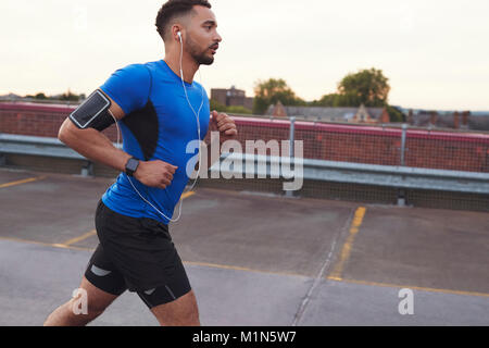 Jeune homme sportif fonctionnant sur une route, side view close up Banque D'Images