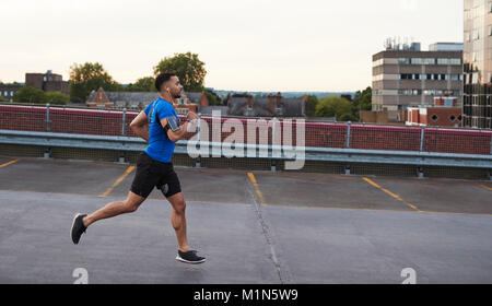 Jeune homme sportif fonctionnant sur une route, side view Banque D'Images