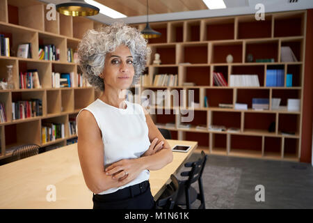 Senior businesswoman standing dans la salle à la recherche d'appareil photo Banque D'Images