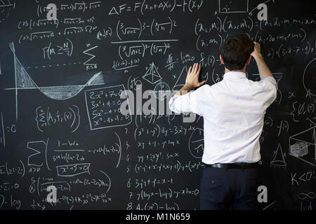 Jeune homme écrit sur tableau noir Banque D'Images