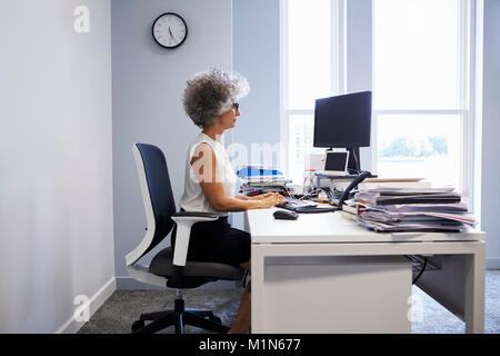 Middle aged businesswoman using laptop computer dans son bureau Banque D'Images
