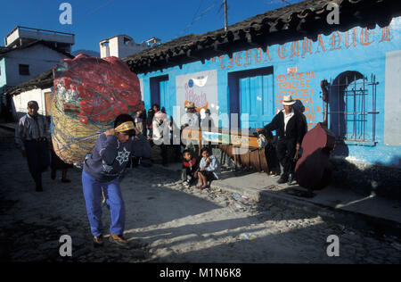 Le Guatemala. Chichicastenango. Homme transportant des marchandises sur le marché de rue. Contexte : bon musicien. A gauche : marimba (instrument typique du Guatemala). Banque D'Images