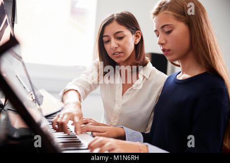 Élève de sexe féminin avec l'enseignant à jouer du piano dans la Leçon de Musique Banque D'Images