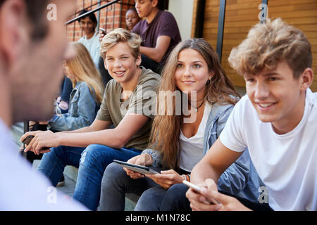 Étudiants adolescents parler à l'enseignant à l'extérieur de bâtiments scolaires Banque D'Images