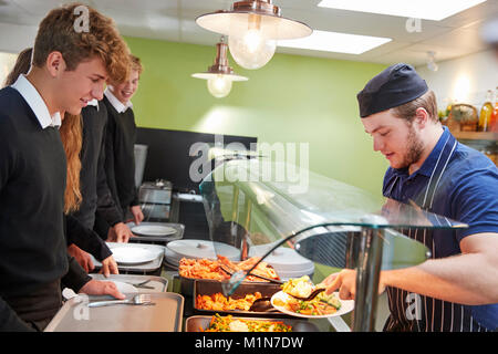 Étudiants adolescents d'être servi en repas de cantine scolaire Banque D'Images