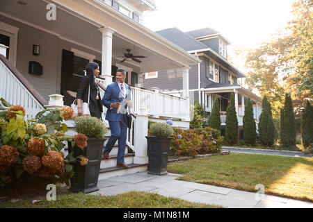 Business Couple laissant Suburban House pour se rendre au travail Banque D'Images