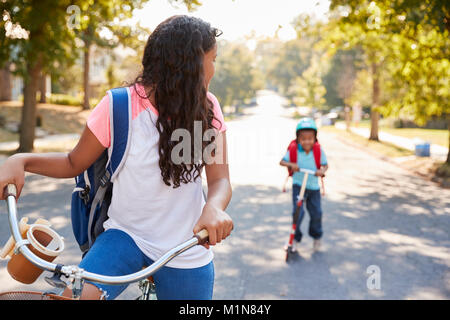 Avec sœur Frère Riding Scooter et vélo à l'école Banque D'Images