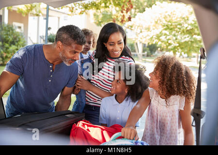 Famille qui part en vacances en voiture charger des bagages Banque D'Images