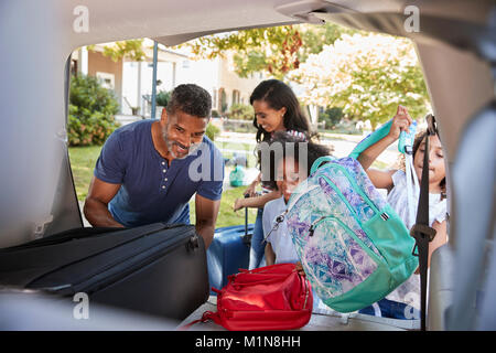 Famille qui part en vacances en voiture charger des bagages Banque D'Images