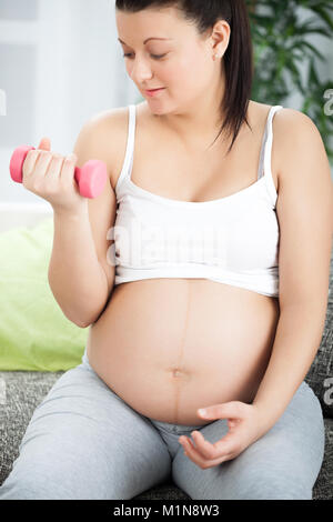 Femme enceinte la levée de poids à la maison Banque D'Images