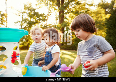 Groupe de jeunes enfants jouant avec de l'eau Table dans jardin Banque D'Images