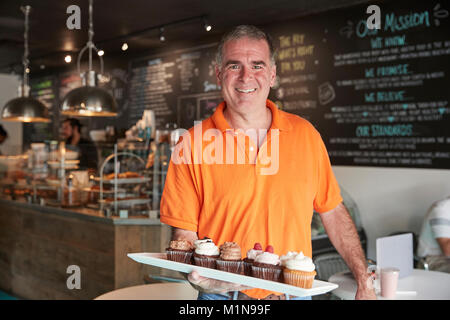 Portrait de l'homme propriétaire avec plateau de muffins dans Coffee Shop Banque D'Images