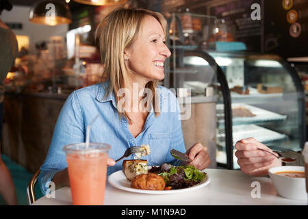 Femme dans un café assis à table en train de manger un déjeuner sain Banque D'Images