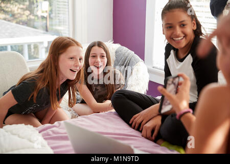 Quatre adolescentes dans la chambre looking at smartphone, Close up Banque D'Images