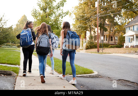 Quatre jeunes filles de l'adolescence à l'école à pied ensemble, vue arrière Banque D'Images