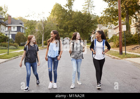 Quatre jeunes adolescentes marcher dans la route, pleine longueur Banque D'Images