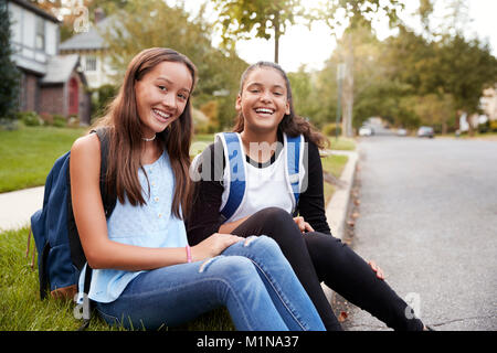 Deux copines adolescentes s'asseoir au bord de la route à la recherche d'appareil photo Banque D'Images
