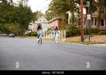 Deux adolescentes équitation vélos dans la distance dans rue calme Banque D'Images