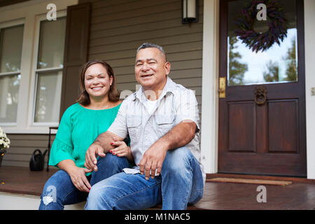 Portrait Of Smiling Senior Couple Sitting in front of their Home Banque D'Images