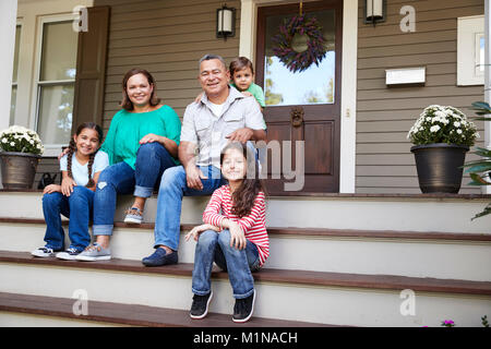 Les grands-parents avec petits-enfants s'asseoir sur les marches menant à la maison Banque D'Images