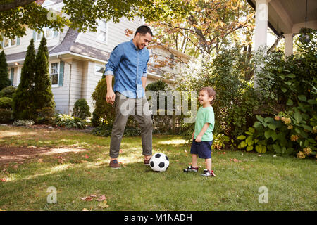 Le père joue au soccer dans jardin avec fils Banque D'Images