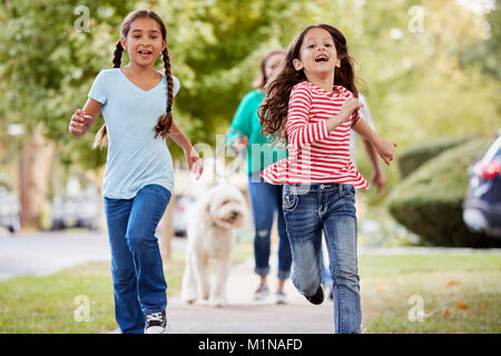 Grand-mère et petites-filles marcher chien le long de la rue de banlieue Banque D'Images