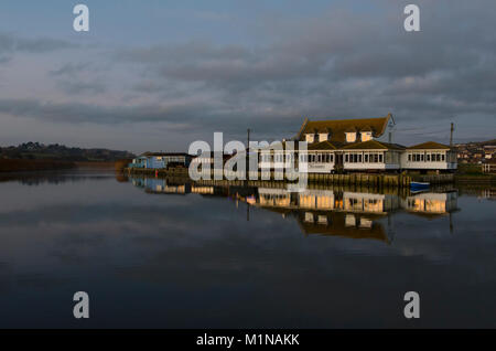 Riverside Cafe de West Bay, avec la lumière du soleil du soir qui se reflète sur windows dans la encore de l'eau du port, Dorset, UK. Banque D'Images